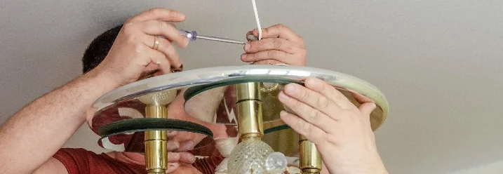 Person montiert Lampe an Decke